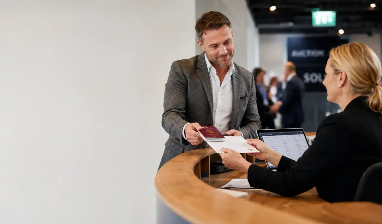 ID to register to bid at auction — buyer presenting passport and proof of address at UK property auction registration desk